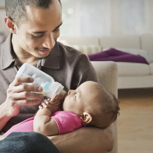 Baby girl drinking her bottle on daddy's lap Baby girl drinking her bottle on daddy's lap